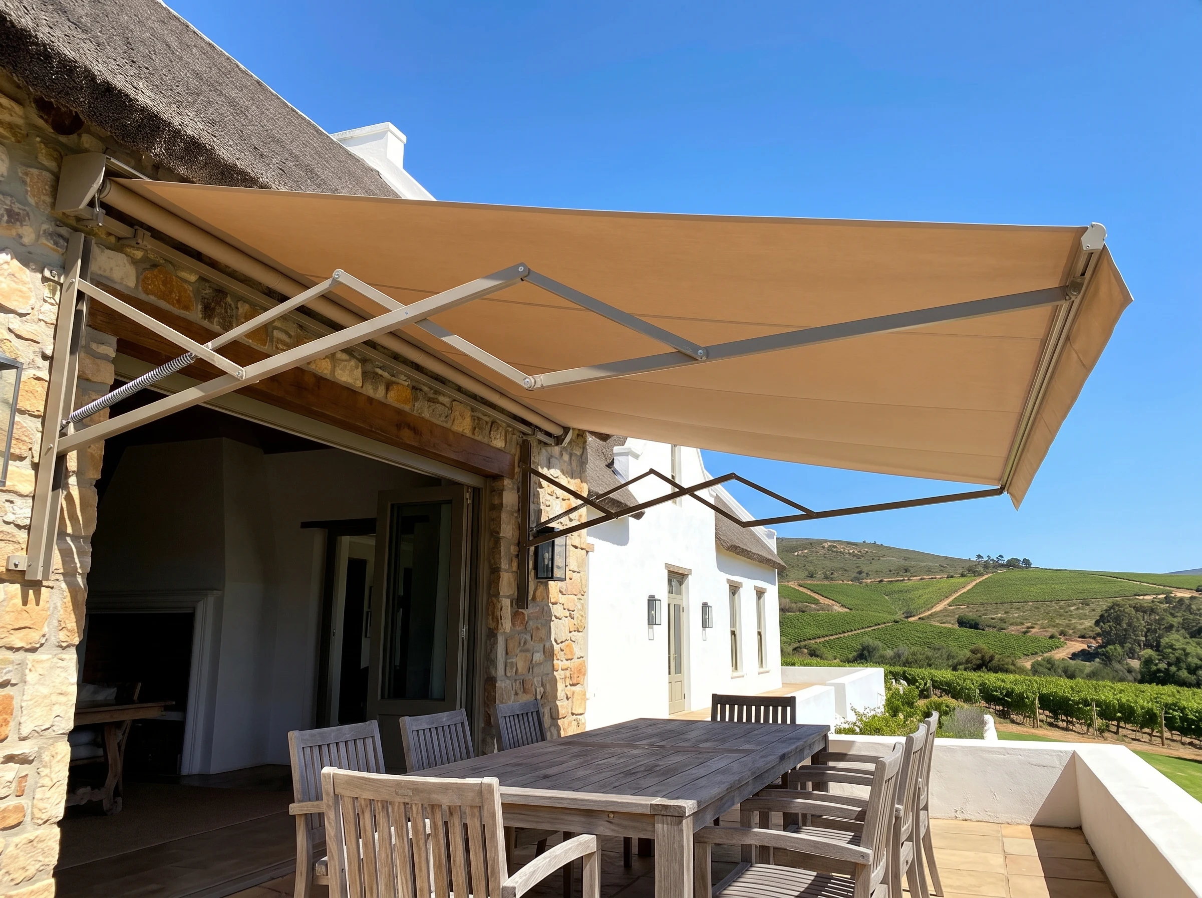 Retractable folding-arm awning extended over a patio table in a Cape Winelands estate home