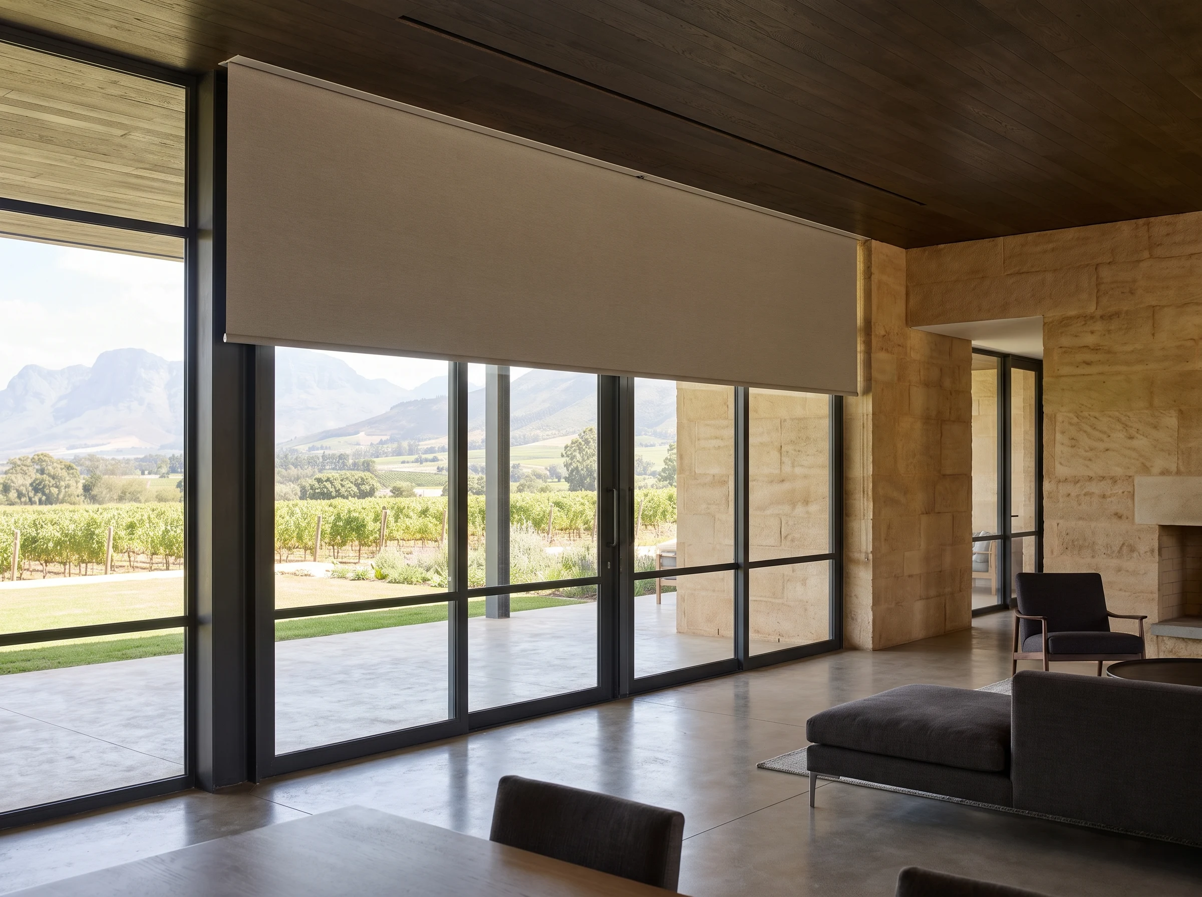 Motorised roller blind emerging from a slim concealed ceiling slot in a Cape Winelands estate home with a frameless glass wall